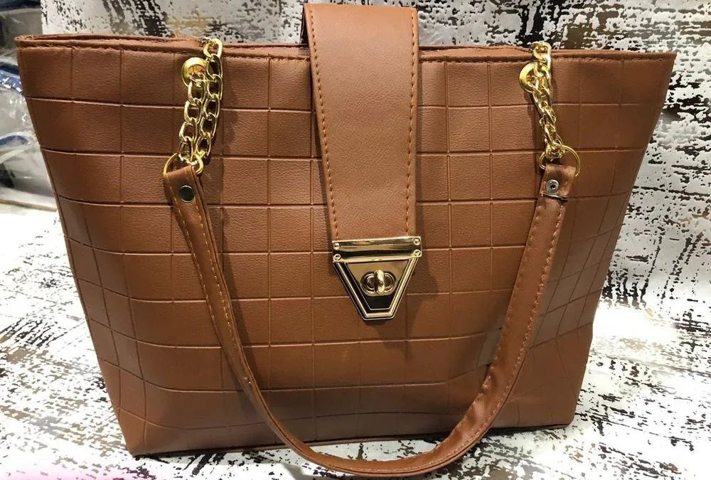 Brown quilted handbag with gold chain and clasp on a textured surface