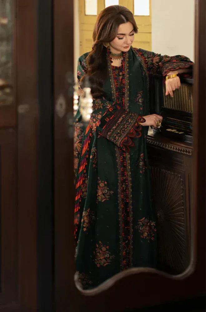 Woman in a dark green embroidered dress standing in front of a mirror.