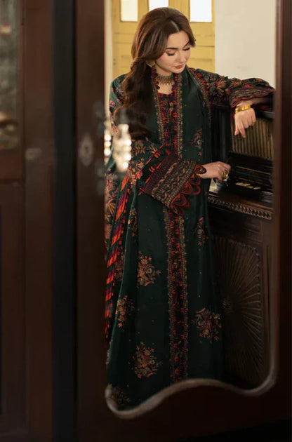 Woman in a dark green embroidered dress standing in front of a mirror.