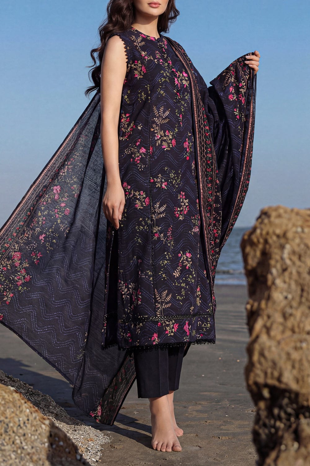Woman wearing a dark floral dress on a beach