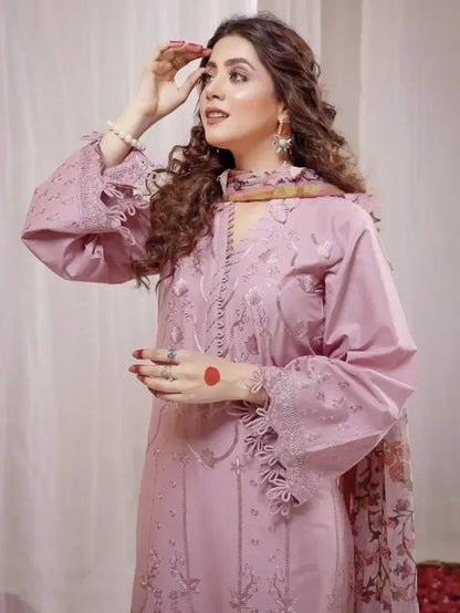 Woman wearing a pink embroidered outfit with a plain background
