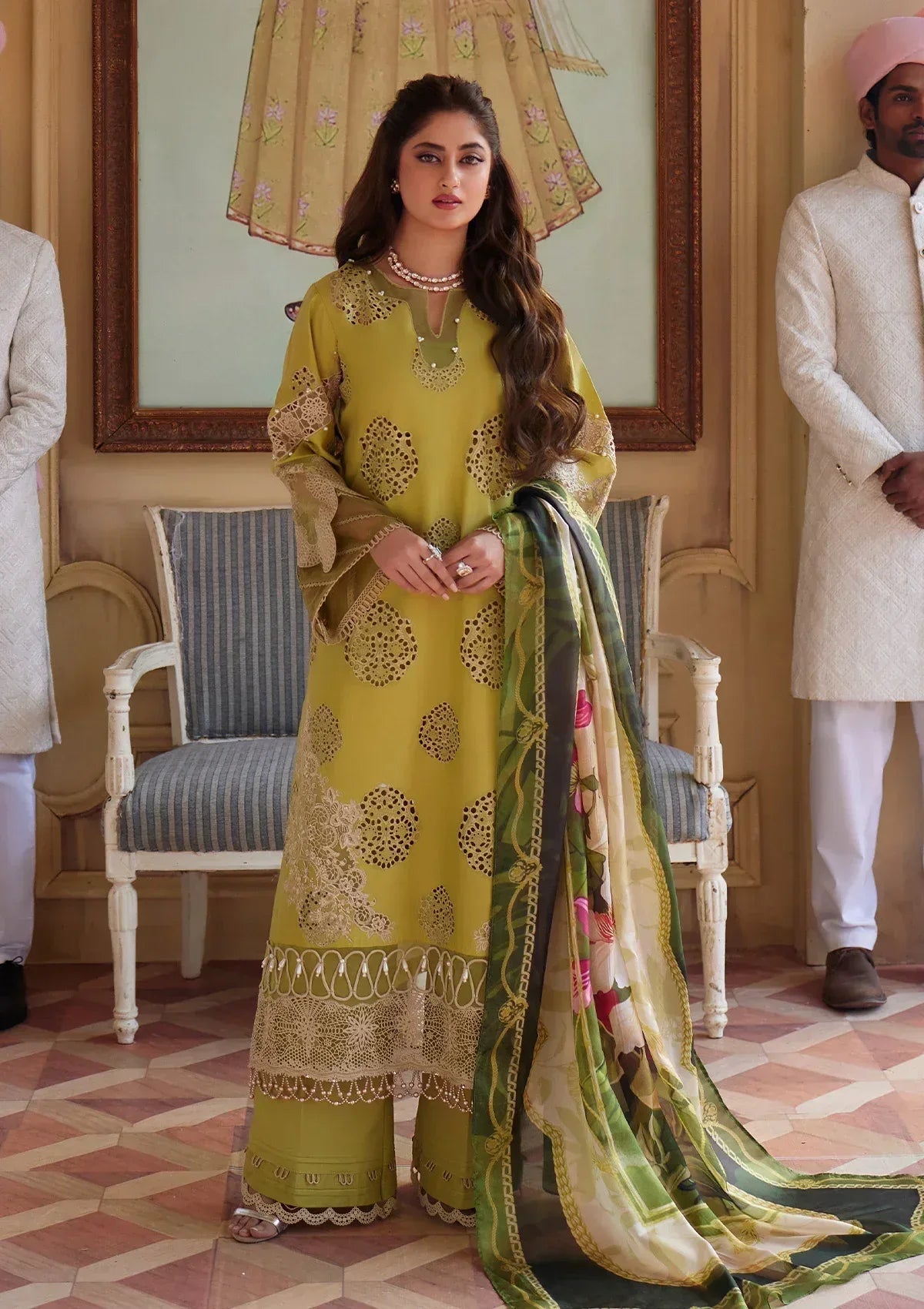 Woman in a yellow traditional outfit with a green dupatta in an indoor setting