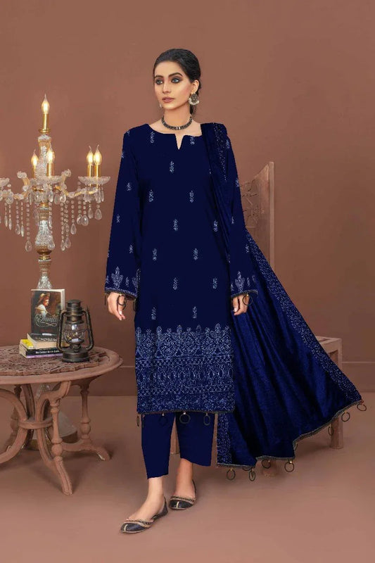 Woman wearing a navy blue embroidered outfit in a decorated room with a chandelier.