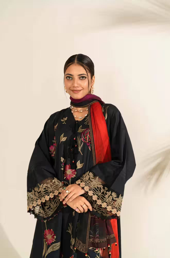 Woman wearing a black embroidered outfit with red accents on a white background