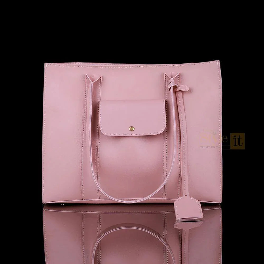 Pink handbag with a strap on a reflective surface against a black background