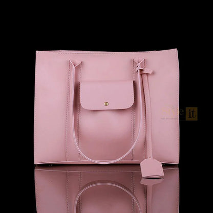 Pink handbag with a strap on a reflective surface against a black background