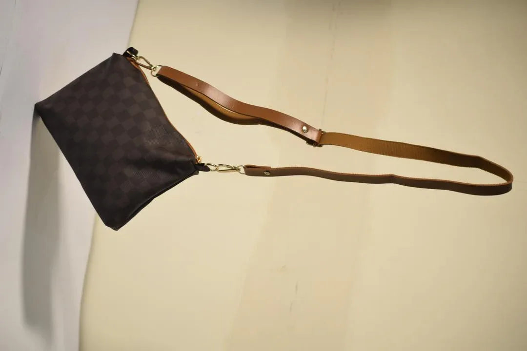 Brown leather handbag with a strap on a beige background