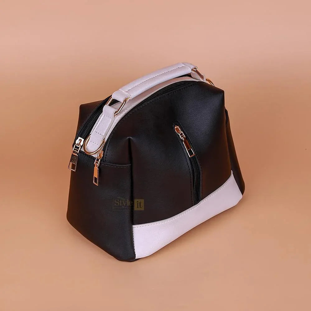 Black and white handbag with gold accents on a beige background