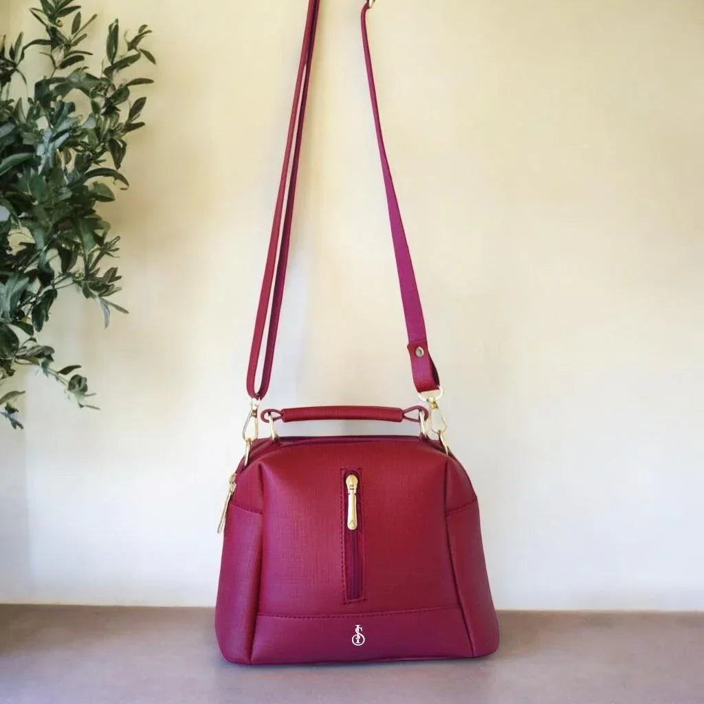Red handbag with a gold zipper on a neutral background