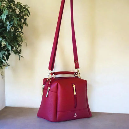 Red handbag with gold accents on a neutral background