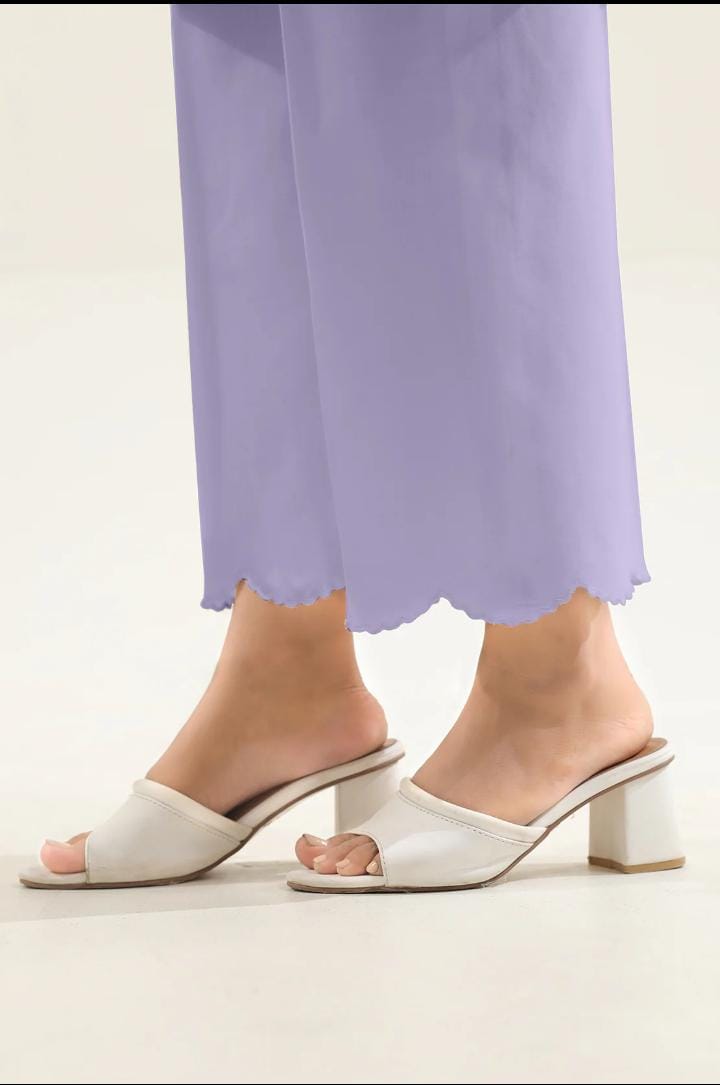 White open-toe heeled sandals worn with light purple pants on a neutral background