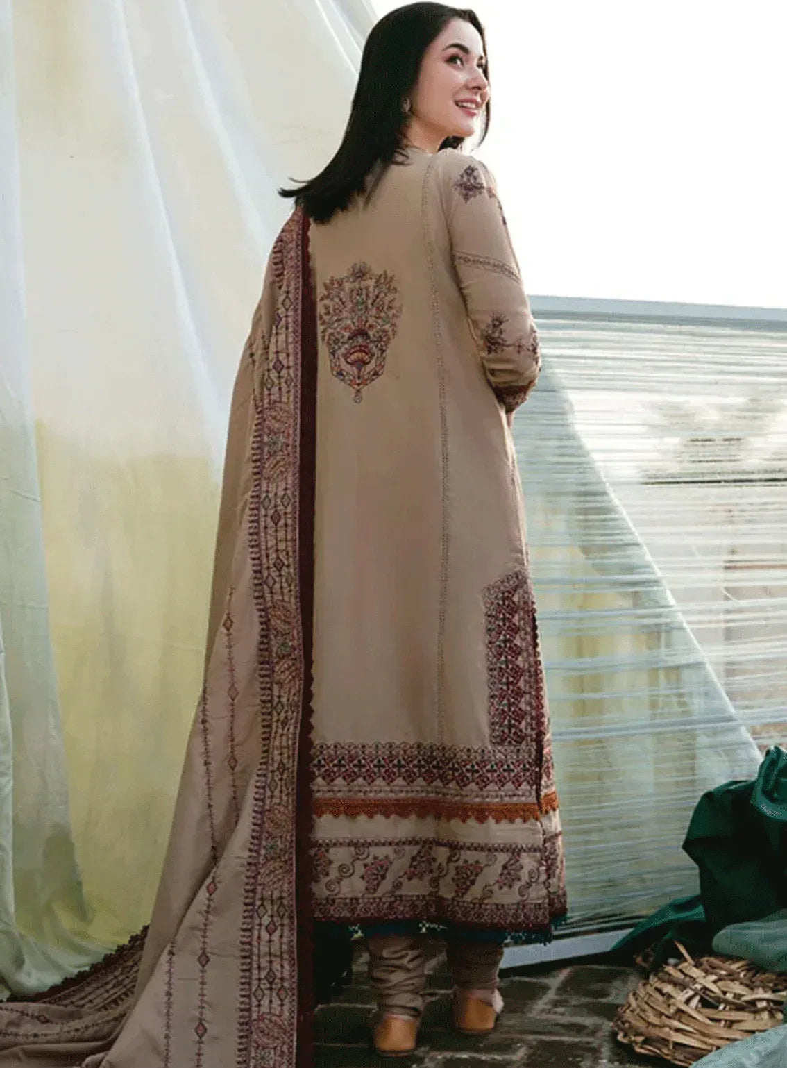 Woman wearing a beige embroidered traditional outfit with a white sheer dupatta.