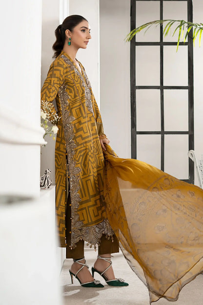 Woman in a mustard yellow traditional outfit with intricate patterns, standing indoors.