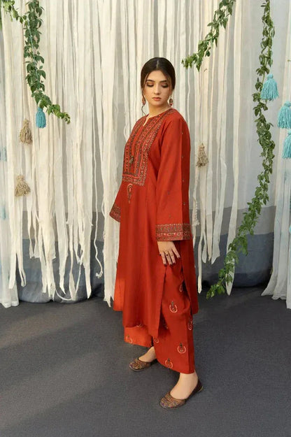 Woman in a red traditional outfit standing in front of decorative white curtains with greenery.