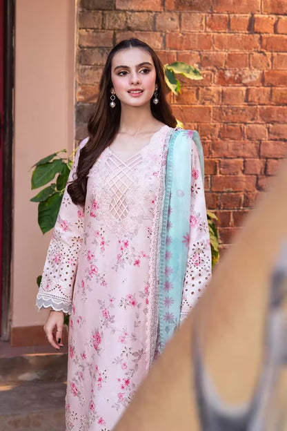 Woman wearing a floral dress with a light blue dupatta against a brick wall.
