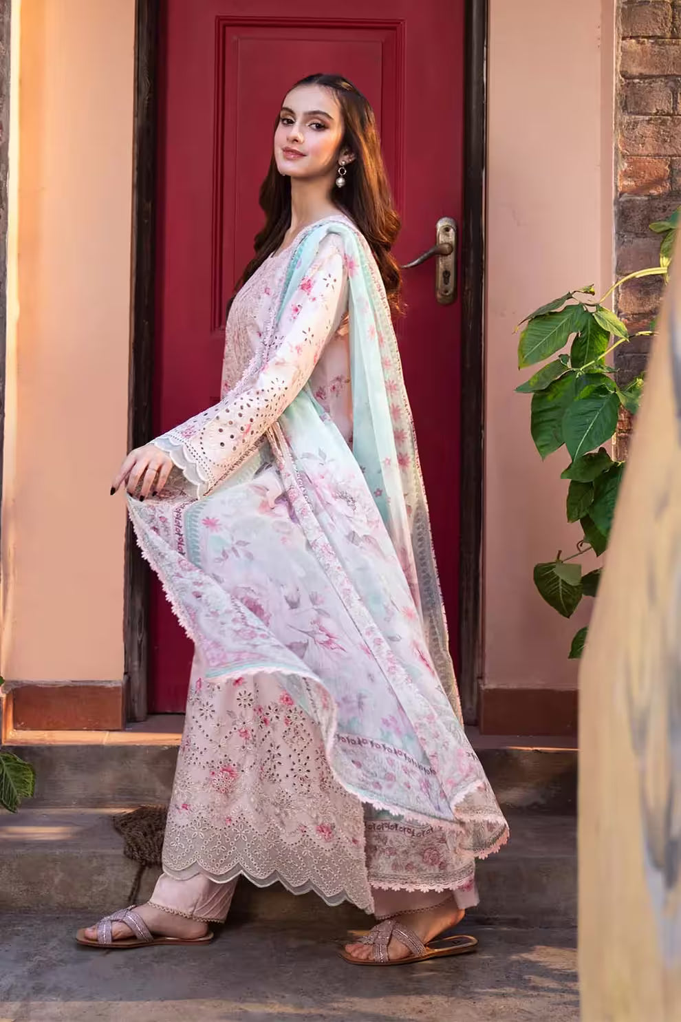 Woman in a traditional outfit standing in front of a red door.