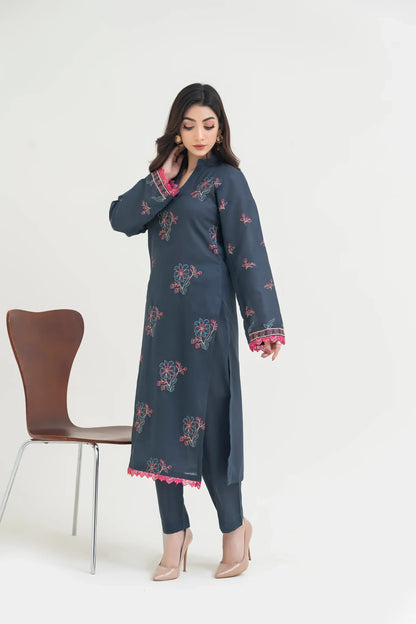 Woman wearing a dark blue embroidered dress with pink details on a white background