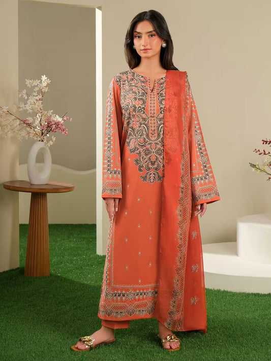 Woman wearing an orange embroidered dress standing in a room with a table and flowers.