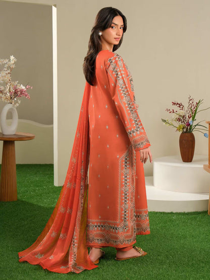 Woman wearing an orange traditional outfit with intricate patterns in a home setting.