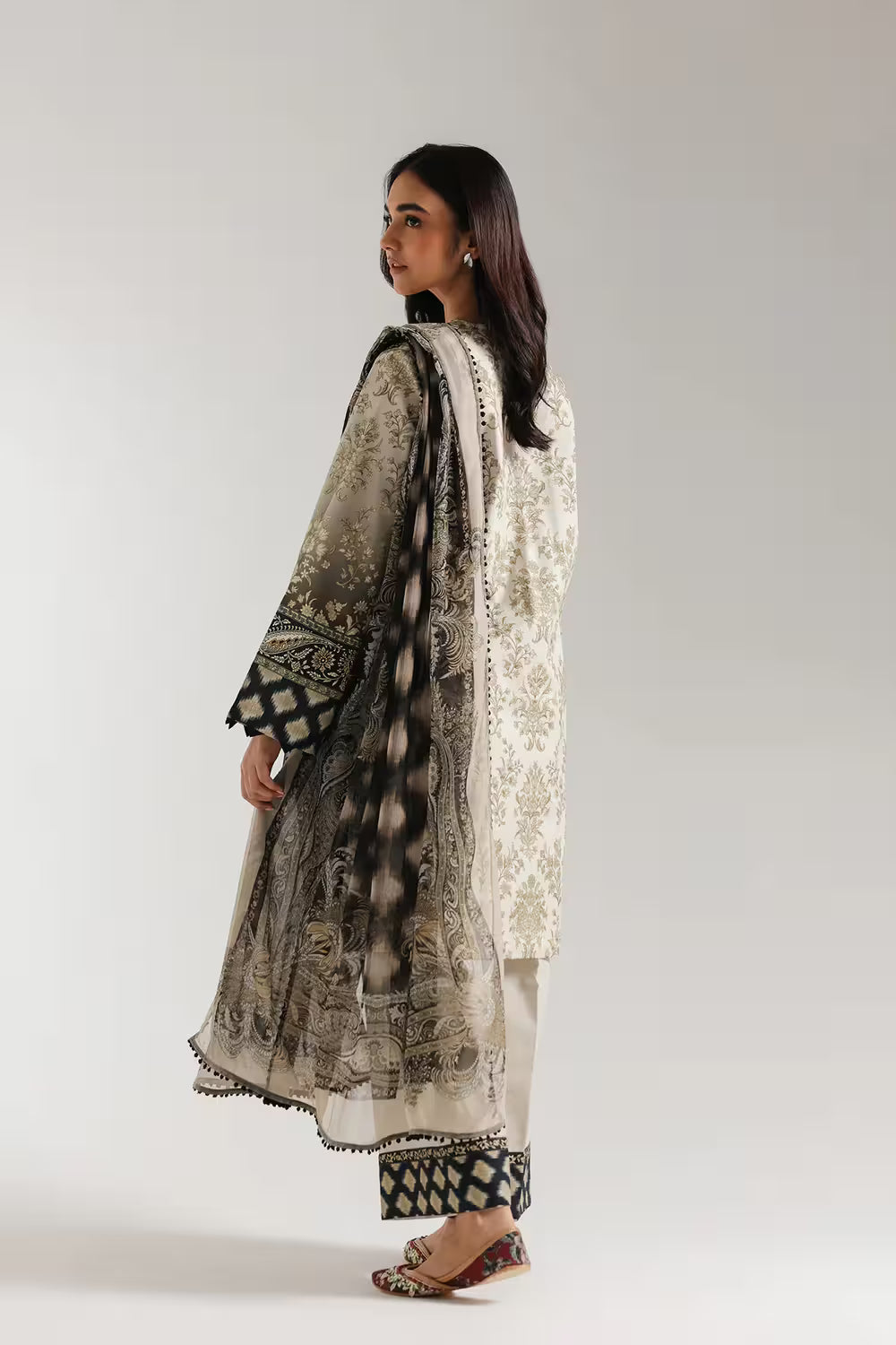 Woman wearing a traditional outfit with intricate patterns on a plain background