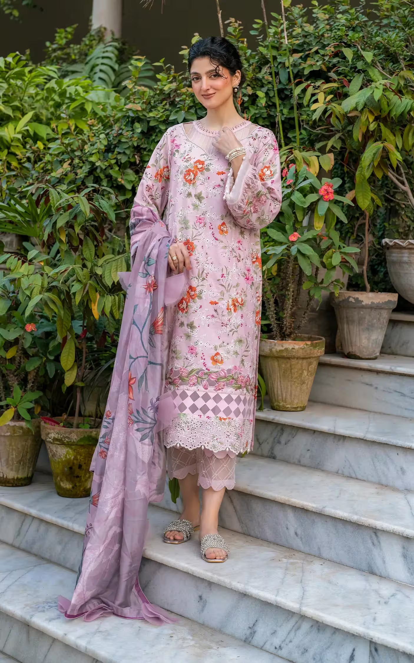 Woman in a floral dress standing on steps with plants in the background