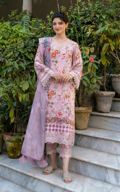 Woman in a pink floral outfit standing on steps with greenery in the background