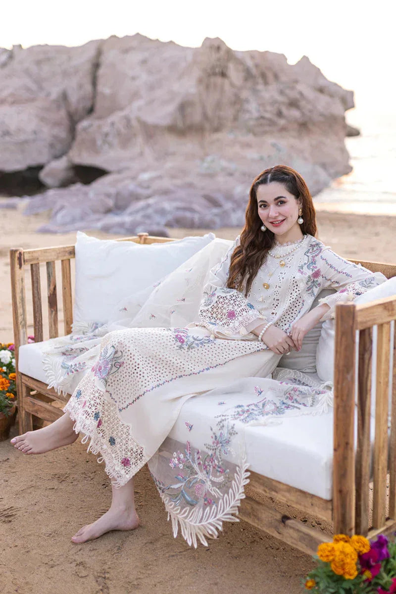 Woman in a floral dress sitting on a wooden bench by the beach.