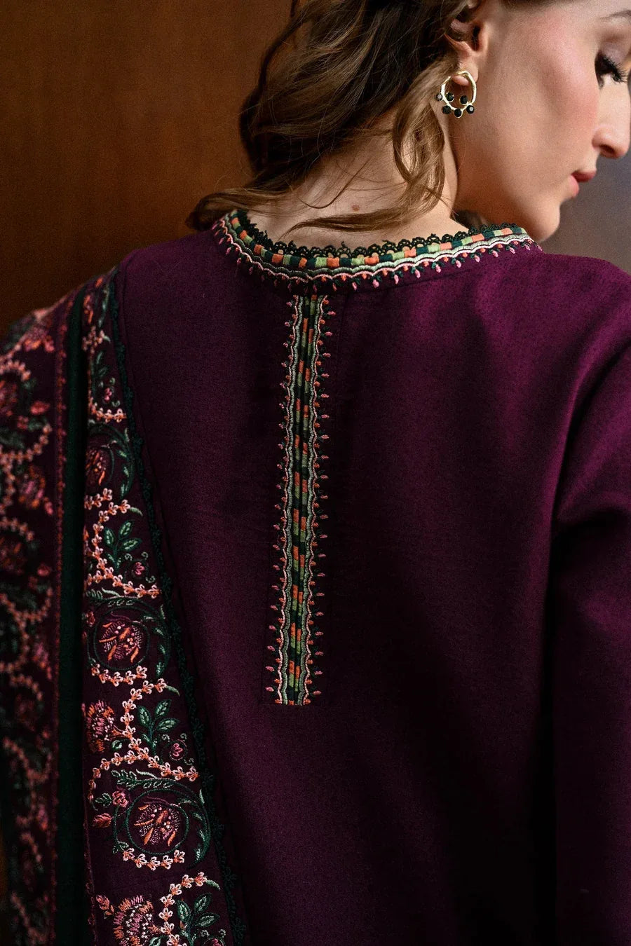 Close-up of a person wearing a dark purple garment with intricate embroidery on the back.