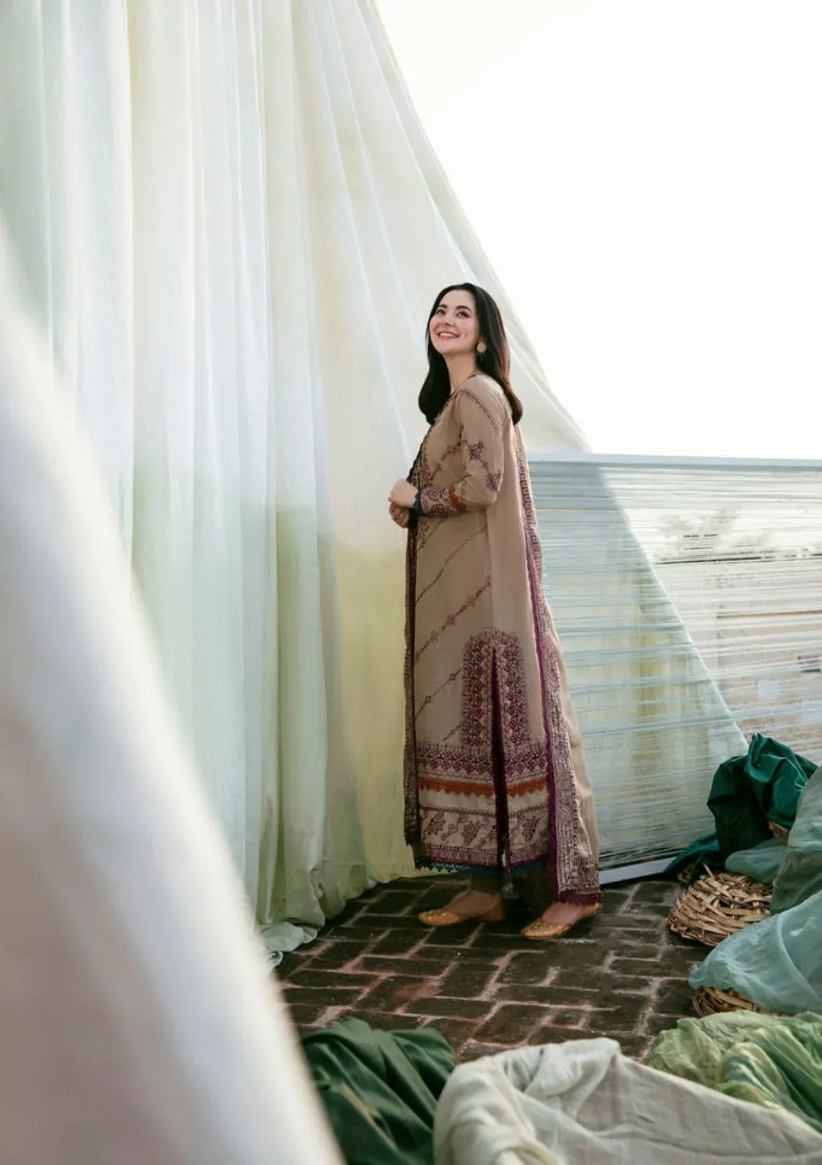 Woman in a patterned dress standing in a room with light filtering through curtains