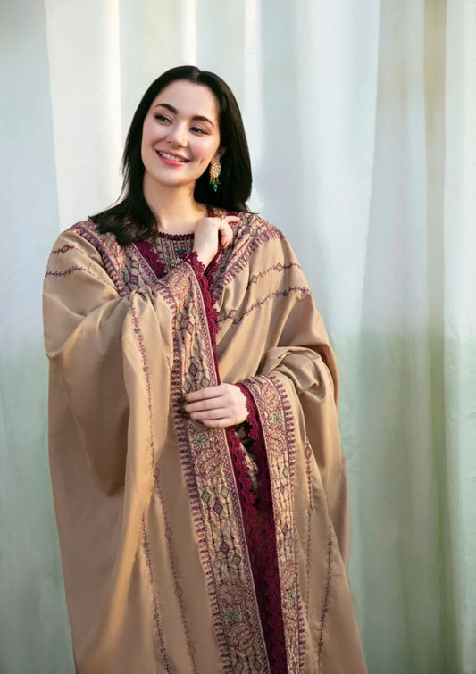 Woman wearing a traditional outfit with intricate patterns against a light curtain background
