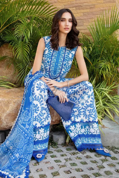 Woman in a blue and white patterned outfit sitting outdoors with plants in the background
