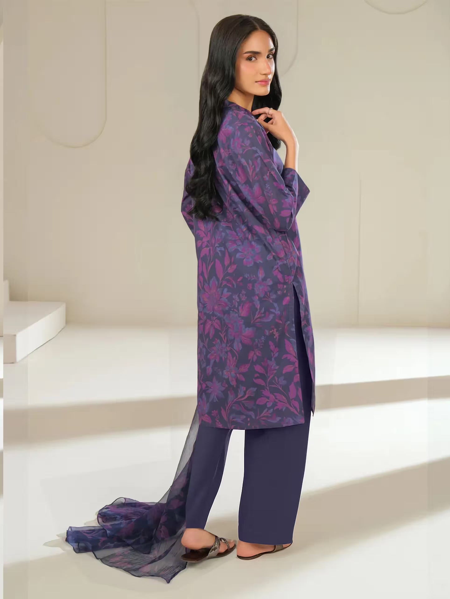 Woman wearing a purple floral outfit in a minimalistic setting