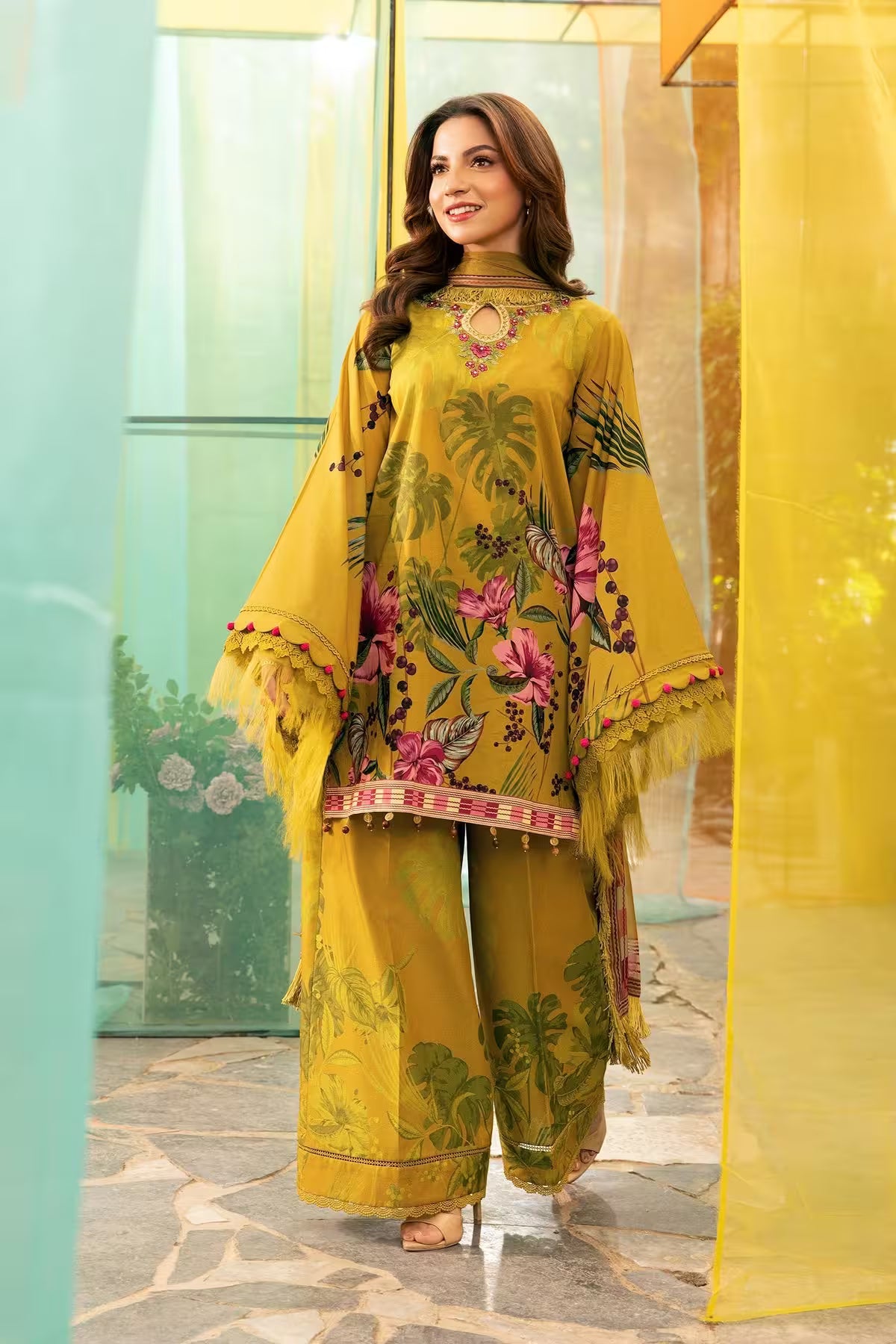 Woman wearing a yellow floral outfit standing in front of a glass door.