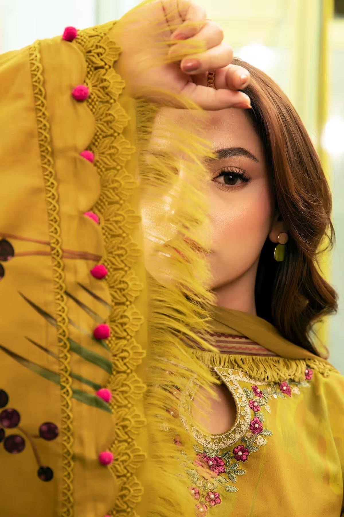 Woman wearing a yellow embroidered traditional outfit with pink embellishments.