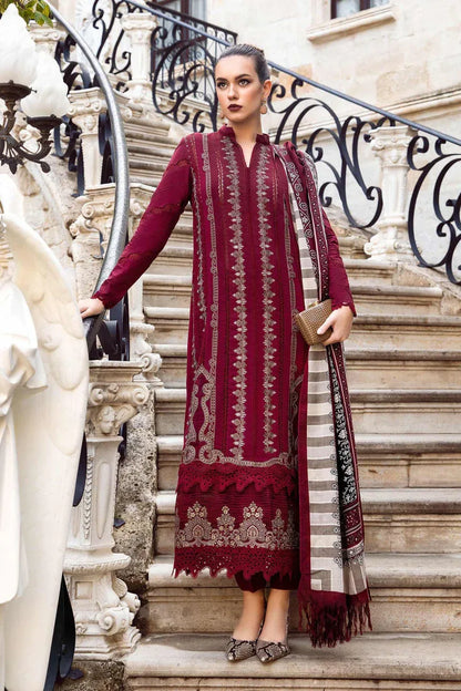Woman in a burgundy traditional outfit with intricate patterns standing on a decorative staircase.