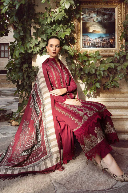 Woman in a red traditional outfit with intricate patterns sitting on steps surrounded by greenery.
