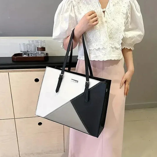 Person holding a black and white handbag in an indoor setting