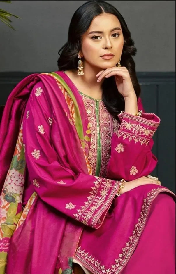 Woman wearing a vibrant pink traditional outfit with intricate patterns against a neutral background
