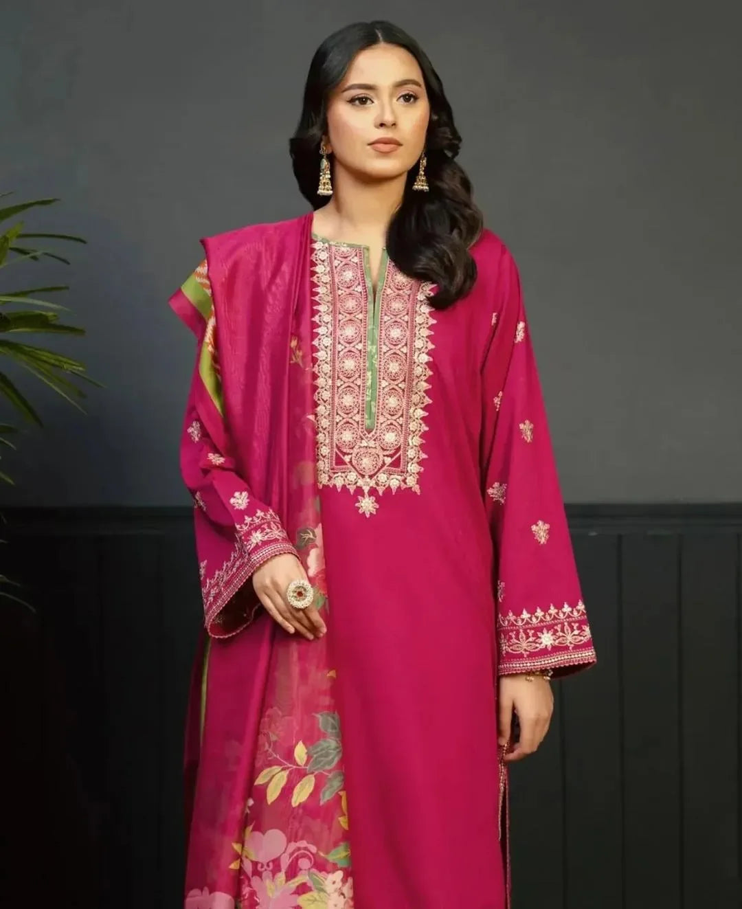 Woman wearing a pink embroidered traditional outfit against a dark background
