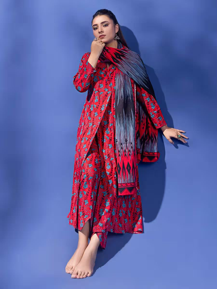 Woman wearing a red and black patterned outfit with a long scarf against a blue background