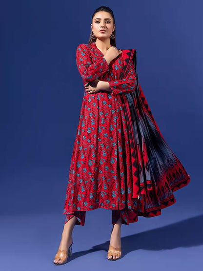 Woman wearing a red and blue patterned dress with a black and red scarf against a blue background