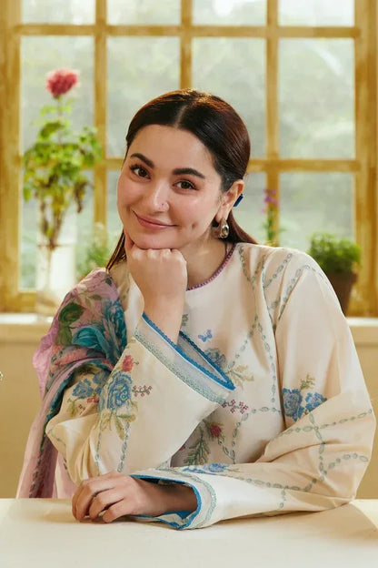 Woman in a floral outfit sitting indoors with a window in the background