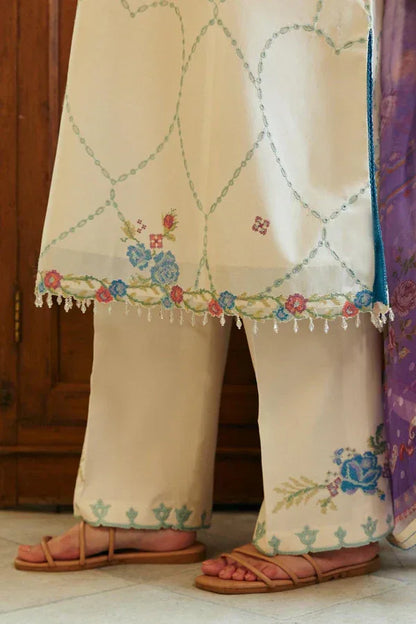 Beige embroidered traditional outfit with floral patterns on a wooden floor.