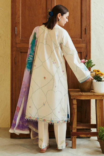 Woman wearing a traditional outfit with a colorful dupatta in a home setting.