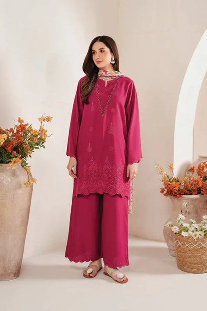 Woman wearing a pink traditional outfit with floral decorations in a decorated room.