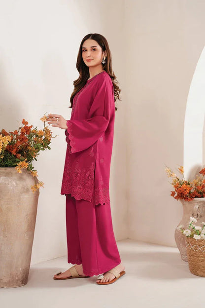 Woman in a magenta outfit standing in a decorated room with flowers and vases.