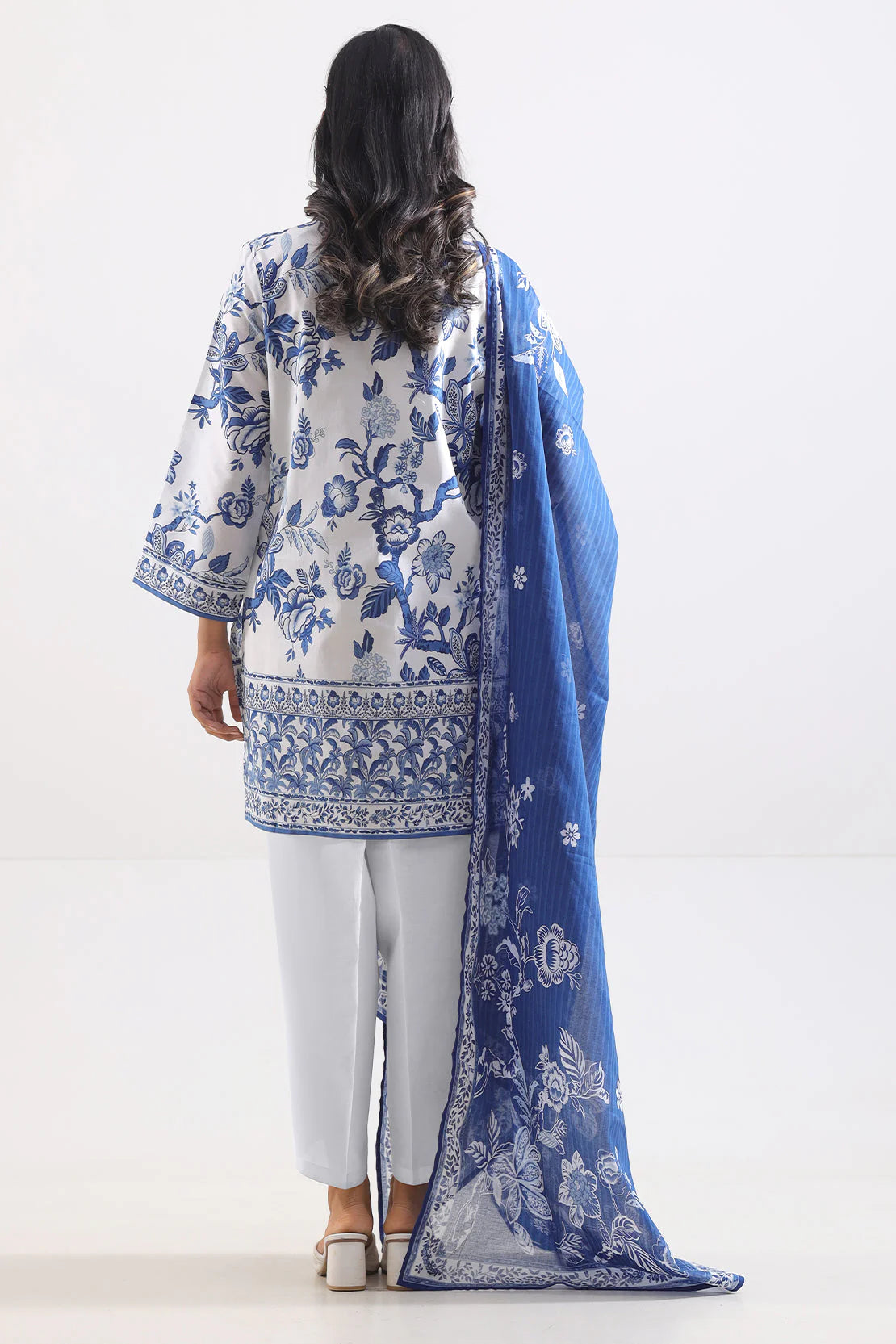 Woman wearing a blue and white floral outfit with a matching dupatta on a white background