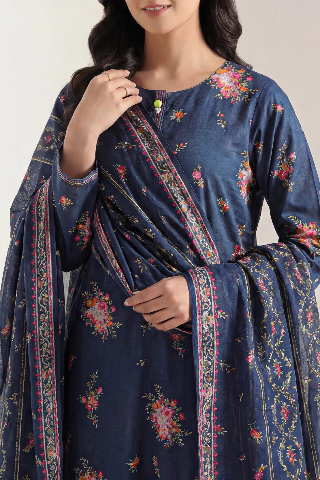 Woman wearing a navy blue traditional outfit with floral patterns on a plain background