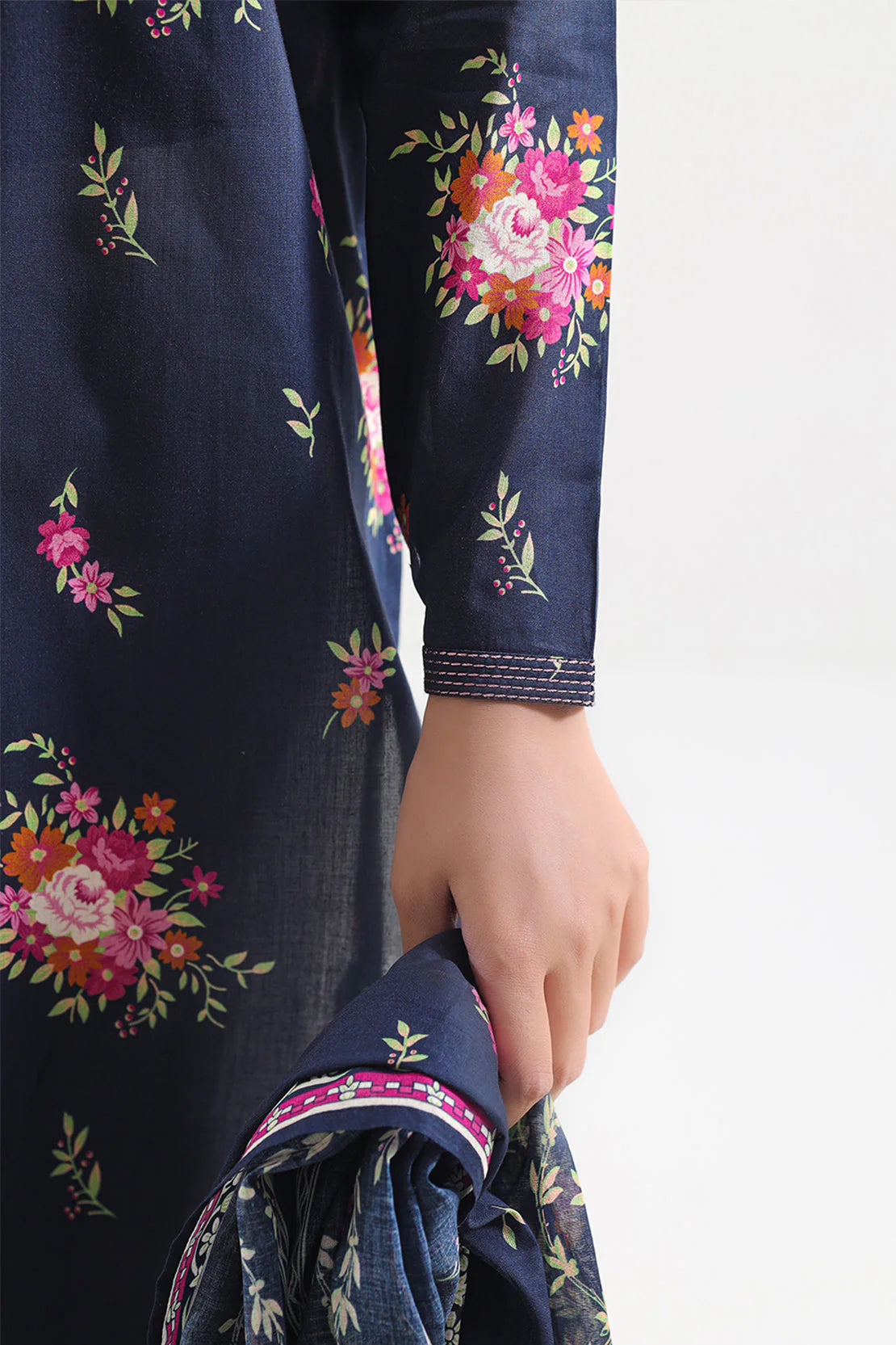 Navy blue fabric with floral embroidery held by a hand on a white background