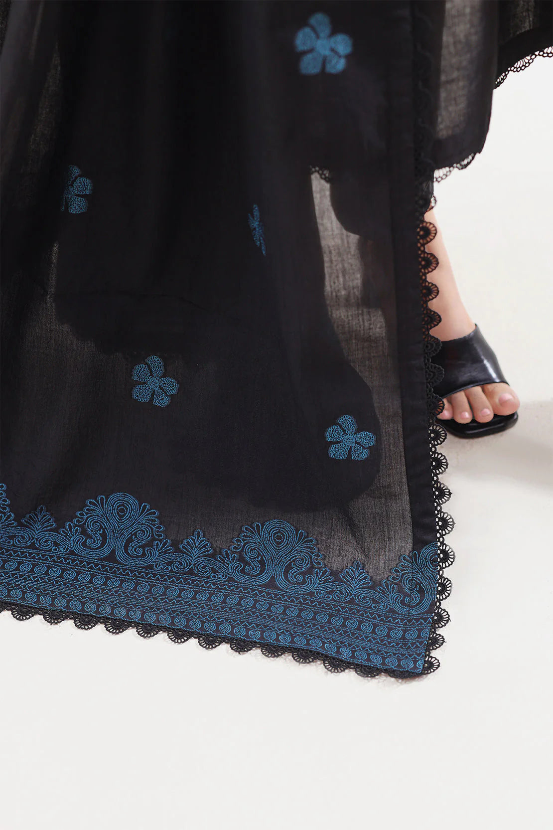 Black garment with blue floral embroidery on a white background
